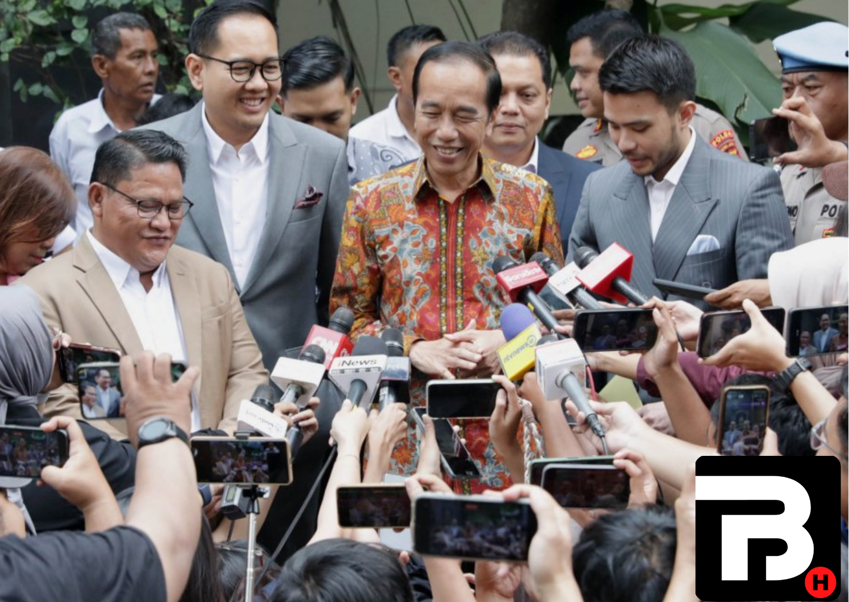 Mantan Presiden Joko Widodo mengenakan batik sedang berbicara di hadapan wartawan yang mengangkat ponsel dan mikrofon untuk merekam pernyataannya